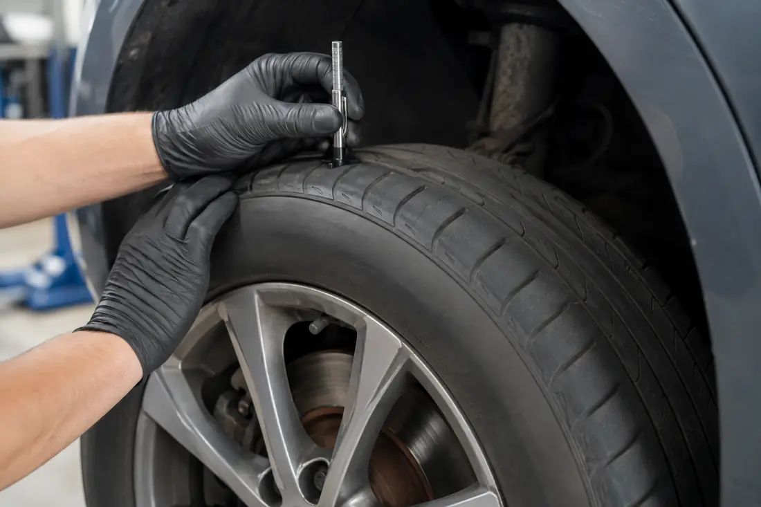 Tire tread being measured beside a visible brake assembly
